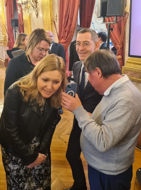 Mr Manuel Pereira, responsable du Pôle Accessibilité numérique, faisant écouter une synthèse vocale sur un téléphone de type smartphone à la Présidente de l'Assemblée nationale Mme Yaël Braun-Pivet