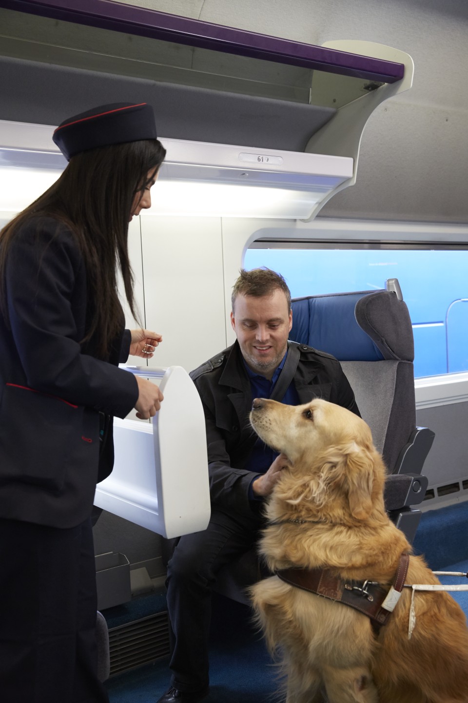 Un membre du personnel SNCF aide une personne aveugle à s'installer à sa place dans un train