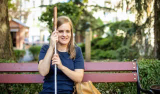 Une jeune femme aveugle assise sur un banc avec sa canne