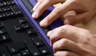 Deux mains écrivant sur une plage braille