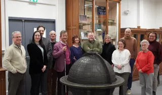 Photo de 12 personnes devant un globe terrestre en braille dans le musée de l'association Valentin Haüy