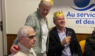 Trois personnes autour d'une table, deux d'entre elles revêtent la couronne qu'elles ont gagné en mangeant la galette des rois