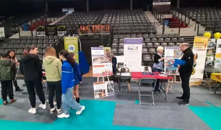 Stand de l'AVH dans une vaste salle de sport, avec des gradins au fond