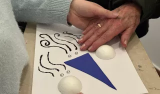 Une main guidée explore un tableau en relief