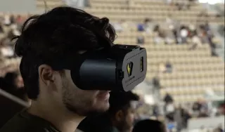 Photographie d'un homme portant un casque basse vision. Au second plan on distingue les gradins d'un stade.