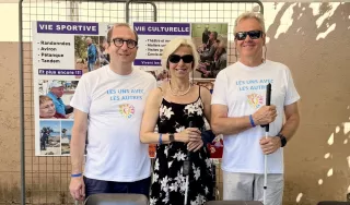 Trois personnes posent devant le stand de l'AVH. Deux d'entre elles portent le T Shirt de l'évènement