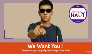 L’image montre un jeune homme malvoyant portant des lunettes noires une canne blanche. Il pointe du doigt vers le spectateur. Il porte un t-shirt sombre avec un badge de l’AVH. En bas de l’affiche il est écrit : We Want You Juste en dessous il est écrit: Deviens les yeux de quelqu’un le temps d’une sortie.