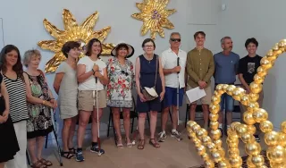 Groupe de personnes autour d'une sculpture formée par des boules de verre de couleur dorée