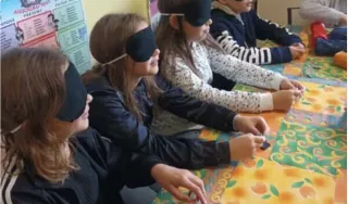 Quatre enfants portent un masque noir et touchent des objets