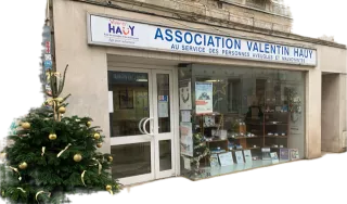 Un sapin de Noël à la robe généreuse décorée de boules et noeuds dorés orne l'entrée de la boutique de l'Association Valentin Haüy.