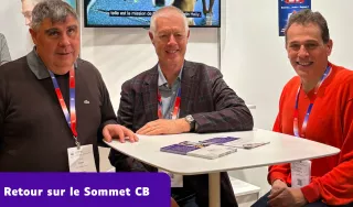Trois hommes, Manuel Perreira, Pascal Bous et Jean-Pierre Carpanini, posent ensemble en souriant derrière une table blanche lors d'un événement. Ils portent des badges autour du cou. En bas à gauche, un bandeau violet affiche le texte "Retour sur le Sommet CB"