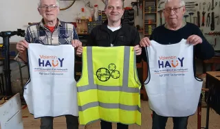Trois personnes de face tiennent des chasubles "Valentin Haüy et Engrenage" lors de la signature de la convention.