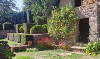 Vue sur une partie du manoir de la Boisnerie : jardin et mur en pierre