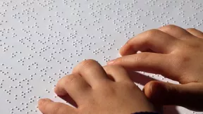 image de main sur une feuille avec du braille écrit