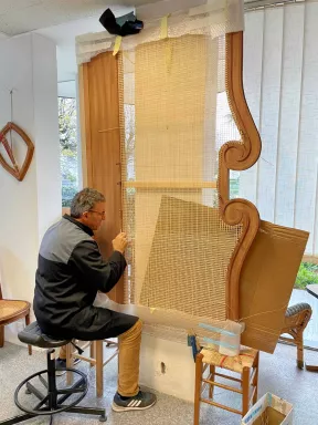 Un artisan en train de faire du cannage