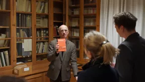 Homme tenant un livre en braille devant la bibliothèque patrimoniale Valentin Haüy