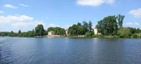 En premier plan, vue de la rivière depuis le bateau, en arrière-plan de belles demeures en pierres du Lot.