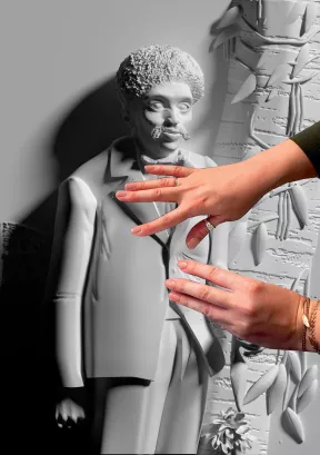 Sculpture d'Alibius réalisée à partir du Portrait d'Edmond Albius devant des lianes de vanille paru en 1863 dans l'Album de l'île de la Réunion d'Antoine Roussin. Deux mains touchent la sculpture.