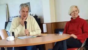 Un homme et une femme assis devant une table. l'homme tient un micro.