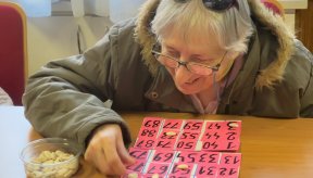 Une personne devant une grille de loto qui pointe les chiffres sortis