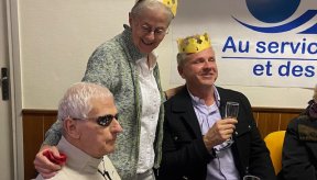 Trois personnes autour d'une table, deux d'entre elles revêtent la couronne qu'elles ont gagné en mangeant la galette des rois