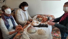 Trois personnes dont les yeux sont bandés explorent avec les mains des reproductions de sculptures