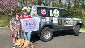 Devant le 4x4 Iris, Laure, Geneviève la Présidente du comité et son chien guide Neigel présentant la banderole du comité 