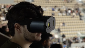 Photographie d'un homme portant un casque basse vision. Au second plan on distingue les gradins d'un stade.
