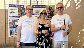 Trois personnes posent devant le stand de l'AVH. Deux d'entre elles portent le T Shirt de l'évènement