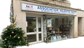 Un sapin de Noël à la robe généreuse décorée de boules et noeuds dorés orne l'entrée de la boutique de l'Association Valentin Haüy.