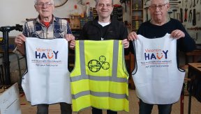 Trois personnes de face tiennent des chasubles "Valentin Haüy et Engrenage" lors de la signature de la convention.